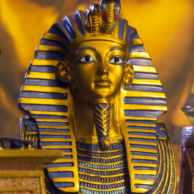 Golden funerary mask replica of Tutankhamun, one of the historical figures who changed the world. This detailed reproduction mimics the original solid gold artifact inlaid with precious stones and colored glass.