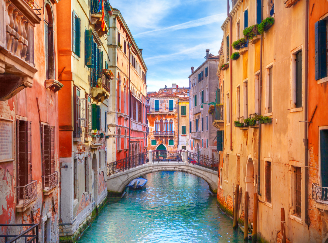 Gondola drifting past colorful buildings on a Venice canal at golden hour