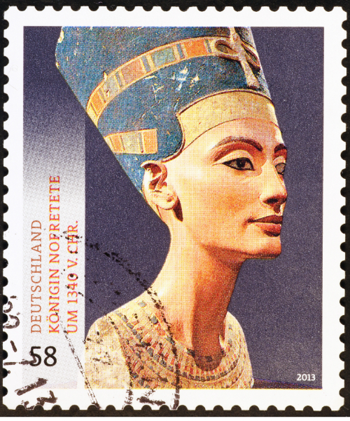 A 58-cent postage stamp issued by Deutsche Post in 2013, featuring the iconic bust of Nefertiti, the Great Royal Wife of Pharaoh Akhenaten. The stamp commemorates the "In the Light of Amarna - 100 Years of the Nefertiti Discovery" exhibition and includes the text "DEUTSCHLAND KÖNIGIN NOPRETETE UM 1340 v. Chr." (Germany Queen Nefertiti around 1340 BC).