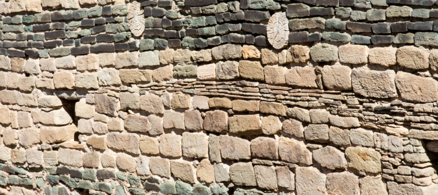 "Panoramic view of ancient stone walls and housing structures at Aztec Ruins National Monument, showcasing the rough-hewn sandstone blocks and interconnected rooms of the ancestral Puebloan community."