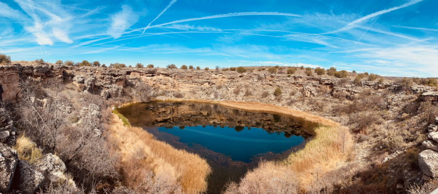 "Panoramic aerial view of Montezuma Well, showcasing the limestone sinkhole, and surrounding landscape with ancient Sinagua cliff dwellings."