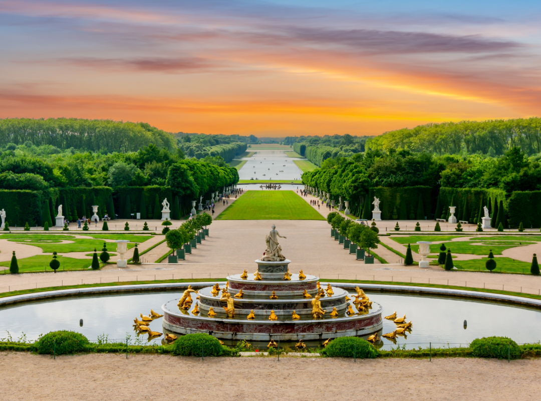 Ornate fountain and geometric hedges in the Gardens of Versailles