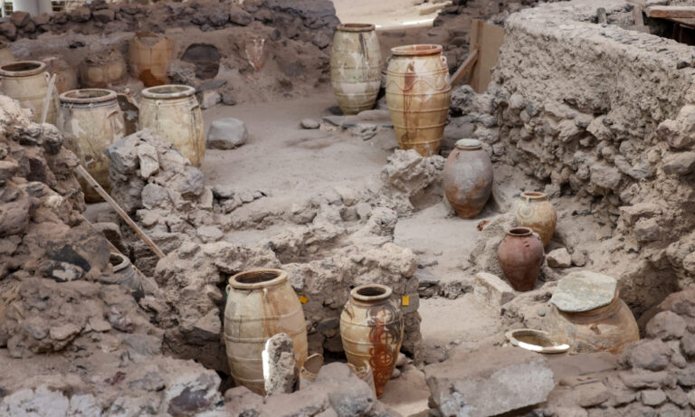 "Archaeologists carefully excavate an ancient site using trowels and brushes, uncovering artifacts and skeletal remains in stratified soil layers under a bright sun. Team members document findings with cameras and notebooks."